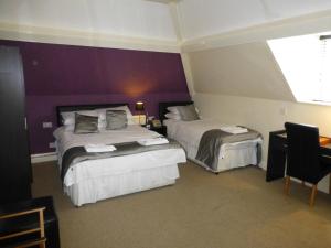 a hotel room with two beds and a window at Maes Manor Country Hotel in Blackwood