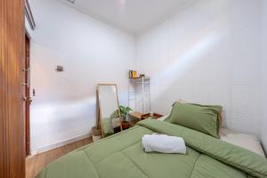 a bedroom with a green bed and a mirror at MONA NEST Canggu 2BR Tiny House with Rooftop and Cozy Workspace in Dalung