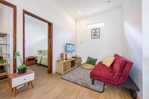 a living room with a red chair and a bedroom at MONA NEST Canggu 2BR Tiny House with Rooftop and Cozy Workspace in Dalung