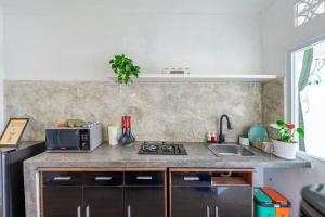 a kitchen with a sink and a microwave at MONA NEST Canggu 2BR Tiny House with Rooftop and Cozy Workspace in Dalung