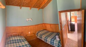 Habitación pequeña con 2 camas y ventana en Cabañas Don Lino, en Cochrane