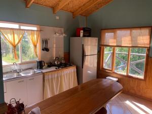 a kitchen with a refrigerator and a table in it at Cabañas Don Lino in Cochrane