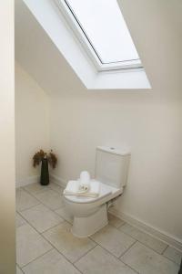 a white bathroom with a toilet with a skylight at Luxury 4Bed Townhouse - Parking+Wi-Fi+Amenities in Nuneaton