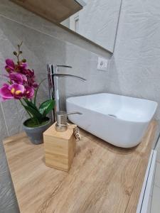 a bathroom sink sitting on a wooden counter with flowers at Gesuiti Home di Agata e Aurora in Catania