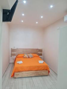 ein Schlafzimmer mit einem Bett mit einer orangefarbenen Decke in der Unterkunft Gesuiti Home di Agata e Aurora in Catania