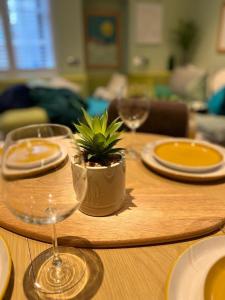 a wooden table with glasses and a potted plant on it at Cambray Apartment in Cheltenham