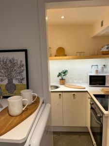 a kitchen with a counter with two mugs on a table at Cambray Apartment in Cheltenham