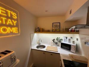cocina con fregadero y microondas en Cambray Apartment en Cheltenham