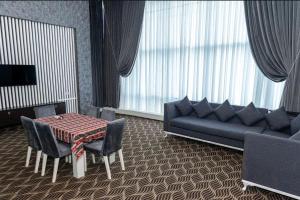 uma sala de estar com um sofá, uma mesa e cadeiras em Titanik Hotel em Baku