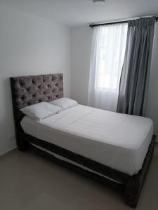 ein Bett in einem Schlafzimmer mit einem Fenster in der Unterkunft Apartamento Hogar fuera de casa in Armenia