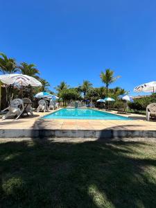 プラドにあるRecanto dos Passárosの- リゾート内のスイミングプール(椅子、パラソル付)