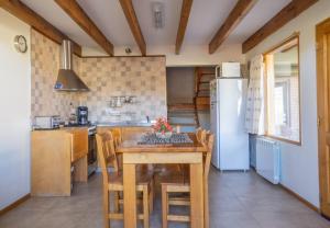 a kitchen with a table with chairs and a refrigerator at Del Sur Apart in Esquel