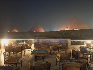 um restaurante com mesas e cadeiras à noite em Yamour Pyramids View no Cairo