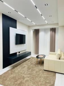 a living room with a white couch and a tv at 3-roomed apartment close to the REGISTAN Ozod Apartments in Samarkand