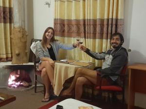 a man and woman sitting at a table with glasses of wine at woods hut in Nuwara Eliya