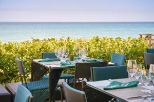 una mesa con copas de vino y el océano en el fondo en The Hillsboro powered by Sonder, en Deerfield Beach