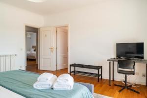 - une chambre avec un lit, un bureau et une télévision dans l'établissement Villa Privée Prestige, à Cascais