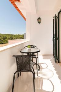 d'une table et de chaises sur un balcon avec une fenêtre. dans l'établissement Villa Privée Prestige, à Cascais