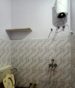 a bathroom with a toilet and a light on the wall at Gokulam Villa in Udaipur