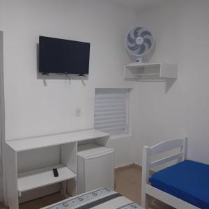 a white room with a tv and a bed at Pousada Aconchego in Ilha Comprida