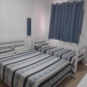 two beds in a room with blue curtains at Pousada Aconchego in Ilha Comprida