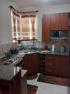 a kitchen with wooden cabinets and a sink and a stove at Monet's sweet Haven in Spanish Town