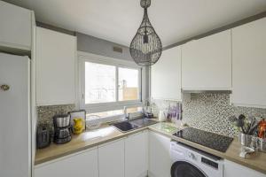 kuchnia z białymi szafkami, umywalką i oknem w obiekcie Appartement Labrouste et son balcon - Welkeys w Paryżu