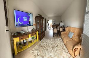 uma sala de estar com um sofá e uma televisão de ecrã plano em Residencial Marina em Florianópolis