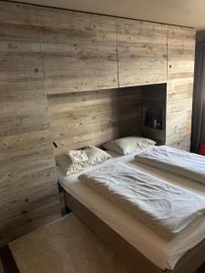 Cama grande en habitación con pared de madera en Nei Y Suredl NeveSole en Corvara in Badia