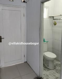 a bathroom with a toilet and a white door at VILLA KID HOUSE BOGOR in Gununggeulis