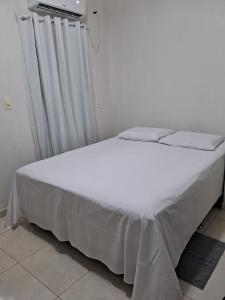 um quarto com uma cama branca com lençóis brancos em Suítes flor de Mandacaru em Piranhas