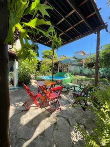 une terrasse avec une table, des chaises et une piscine dans l'établissement Pousada Hostal das Estrelas, à Praia do Frances