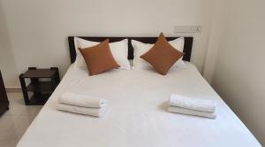uma cama branca com duas toalhas dobráveis em Joywin Apartments Airport transit em Negombo