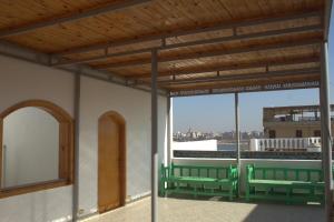un balcone con panche verdi e una grande finestra di Morning Start Apartments a Luxor