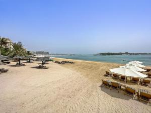 een strand met parasols en stoelen en de oceaan bij VayK - Serene 1BD with Full Sea View on the Palm in Dubai