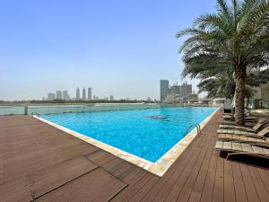 een groot zwembad met palmbomen op een houten terras bij VayK - Serene 1BD with Full Sea View on the Palm in Dubai