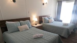 sypialnia z 2 łóżkami i ręcznikami w obiekcie Motel Gentilhommière w mieście Saint-Siméon