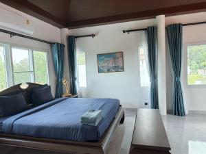 una camera da letto con letto con lenzuola e finestre blu di Pheonix Golf Pool Resort Villa a Ban Huai Yai