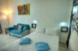 a bedroom with a white bed and a blue chair at Charming 3 storey apartment in Valletta centre, NGRI1-1 in Valletta