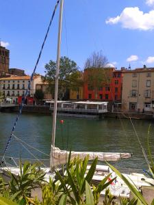 a sail boat is docked in a river with buildings at 3 bedroom apartment overlooking river in Agde