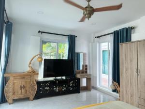 a living room with a flat screen tv and blue curtains at Pheonix Golf Pool Resort Villa in Ban Huai Yai