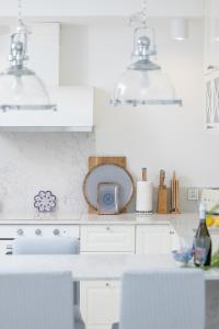 eine Küche mit weißen Schränken und einem Tisch mit Stühlen in der Unterkunft Apartament Ambra Marina - Basen & SPA in Dziwnów