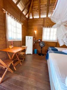 a room with a table and a kitchen with a refrigerator at Atins Beach Houses in Atins