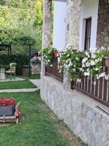 a house with flowers on a stone wall at Rooms and apartmants Mirovic in Kolašin