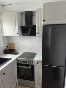 a kitchen with a black refrigerator and white cabinets at Apartament nad Wdą in Świecie