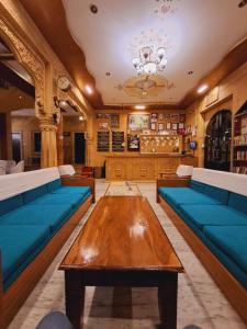 a living room with blue couches and a wooden table at Hotel Tokyo Palace in Jaisalmer