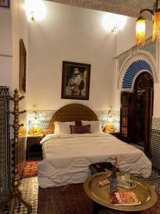 a bedroom with a large bed and a table at Palais Al Firdaous in Fez