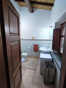 bagno con servizi igienici, lavandino e porta di Casa Lalletta a Nurachi