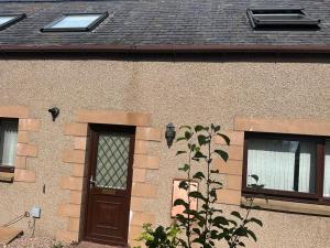 a building with a wooden door and two windows at 3 Bed House Buckie Contractors Business Travellers in Buckie