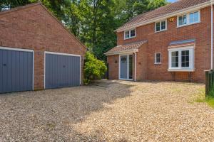 a brick house with two garage doors and a driveway at Woodland Retreat - Garden - Sleeps 11 in Gaywood